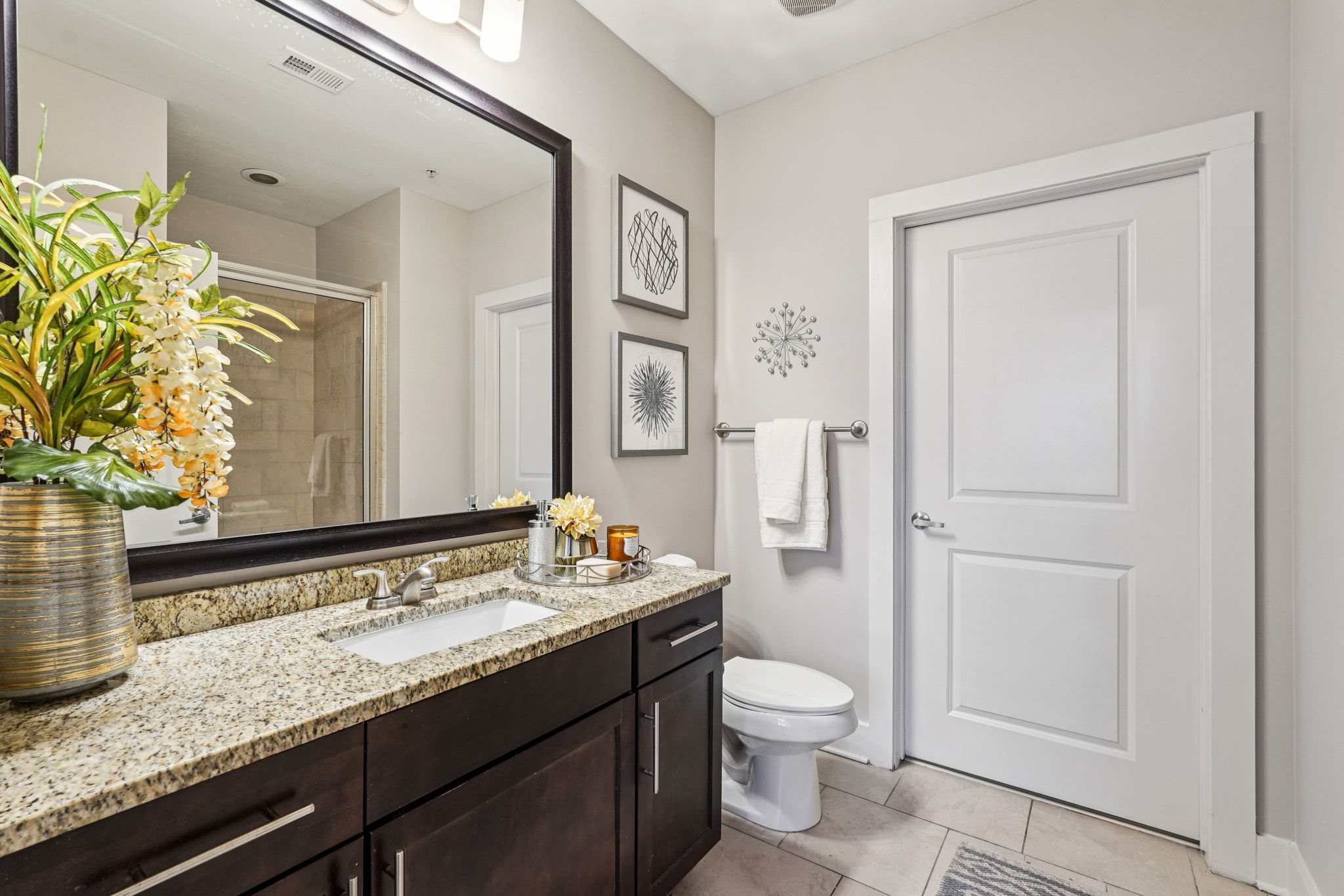 A bathroom with a toilet, sink, and mirror.